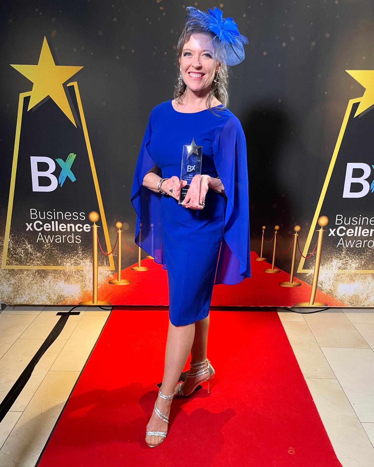 Lara Arden holding her Business xCellence Award on the red carpet